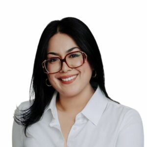 Headshot of a smiling woman with dark hair wearing glasses and a white collared shirt.